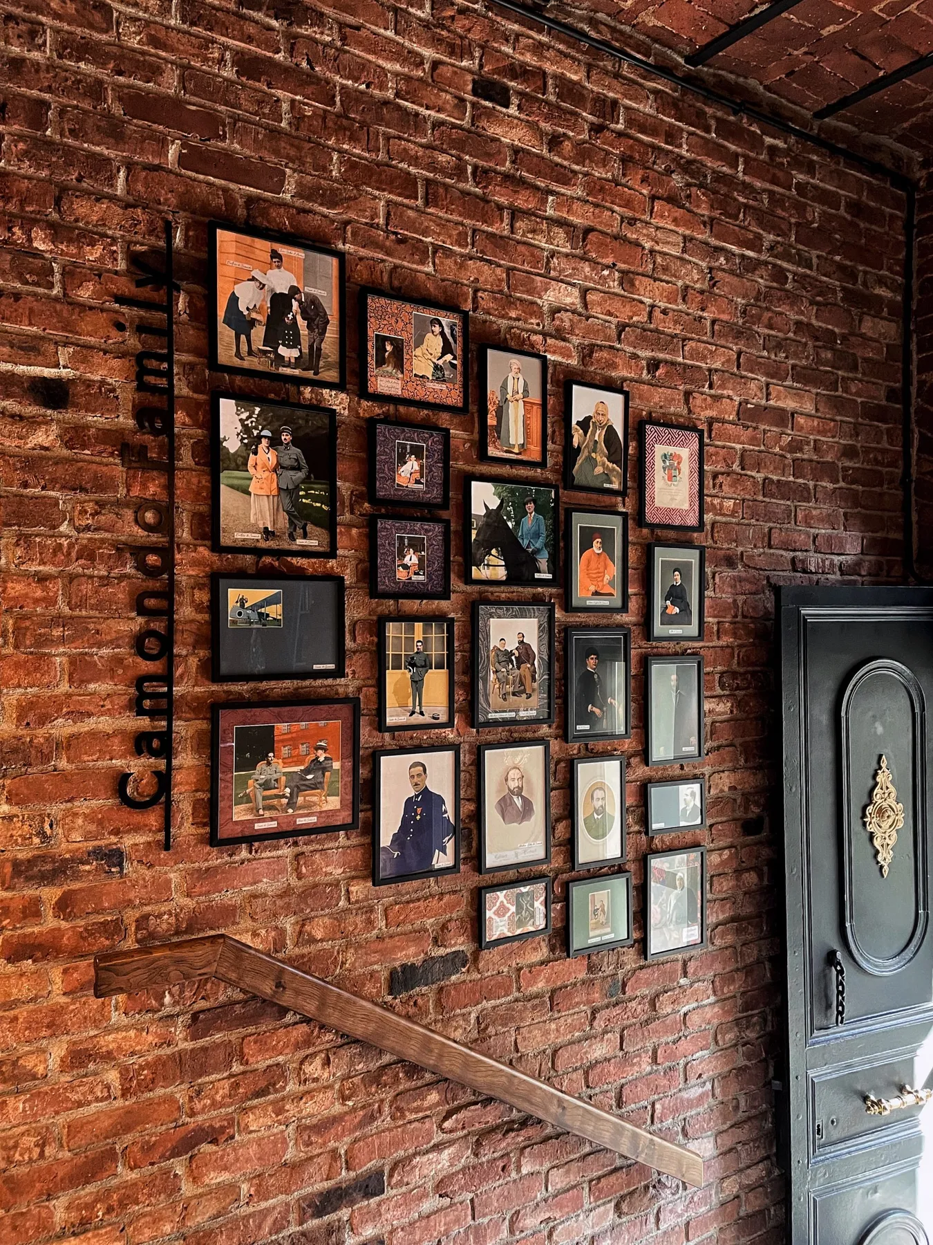 A wall of framed Camondo family photographs on exposed brick