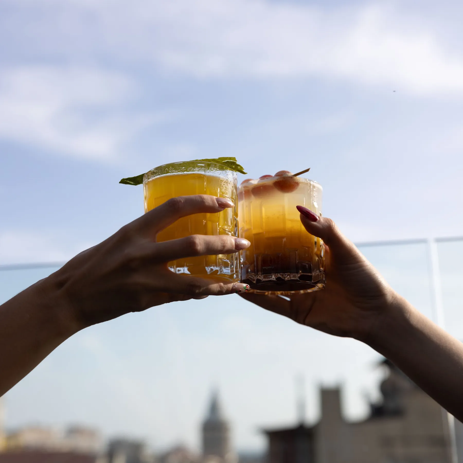 Two cocktails raised against the sky